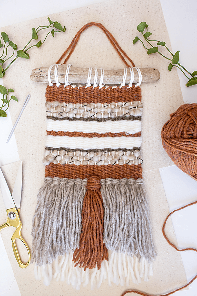 DIY woven wall hanging in browns and taupes on a driftwood hanger.